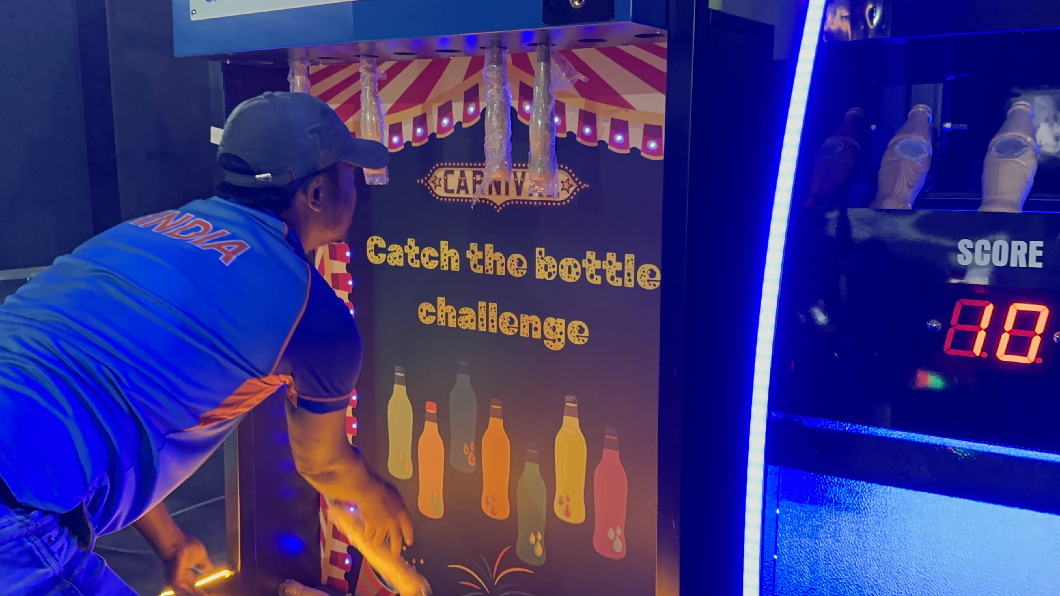 catch the bottle challenge arcade game in action, player catching falling bottle mid-air, LED timer display, vibrant arcade setting, dynamic lighting