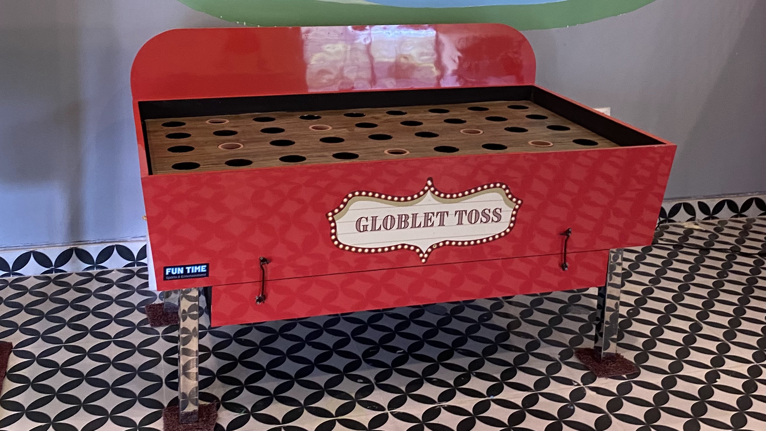 goblet toss carnival game in action, player tossing ball toward elevated goblets, colorful carnival booth, bright lighting, professional photography