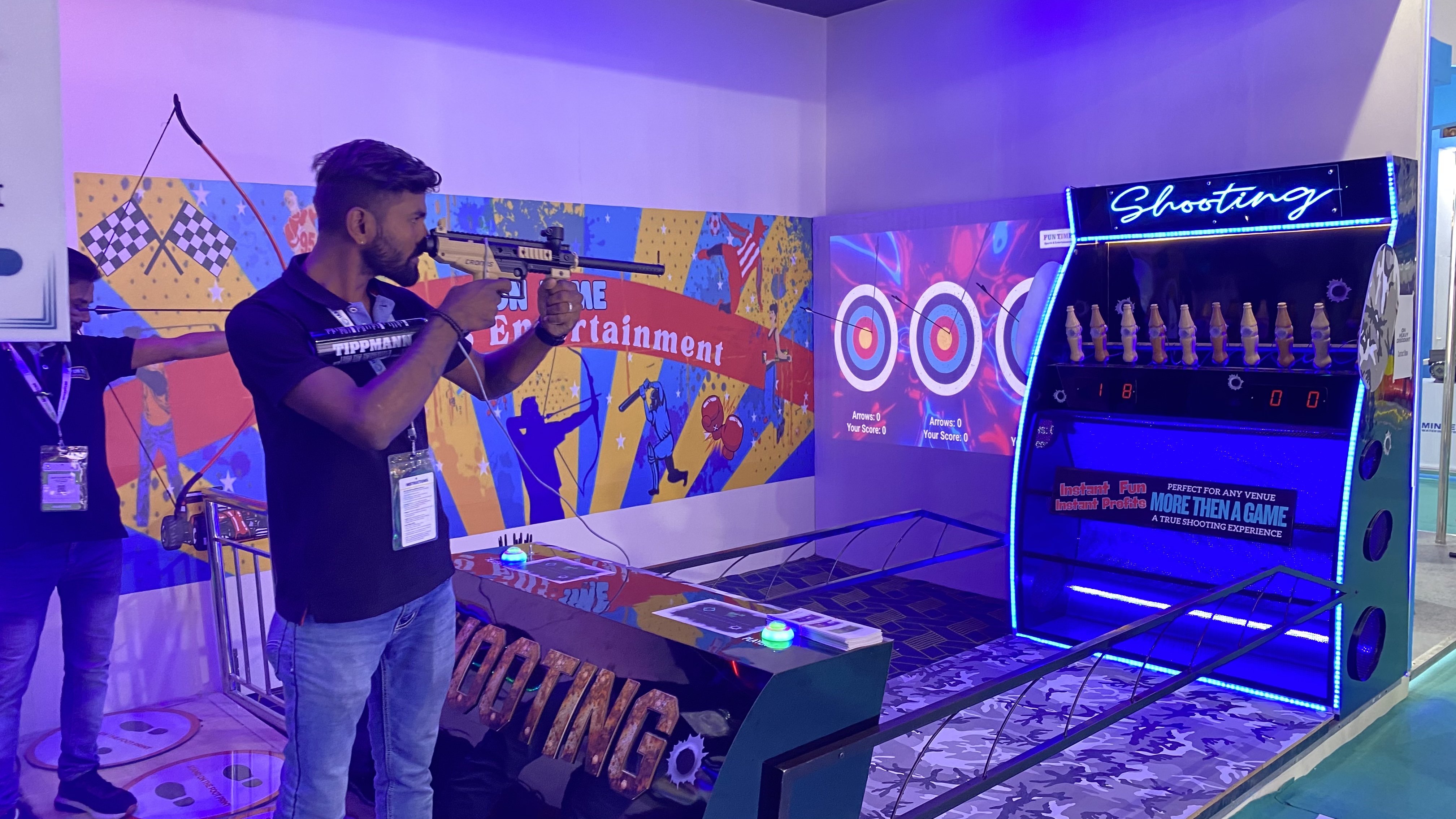 pellet-less shooting arena in action, player aiming CO₂ marker, laser targeting system, smart falling targets, LED scoreboard, immersive indoor setup